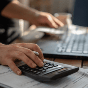man computing costs on a calculator and laptop