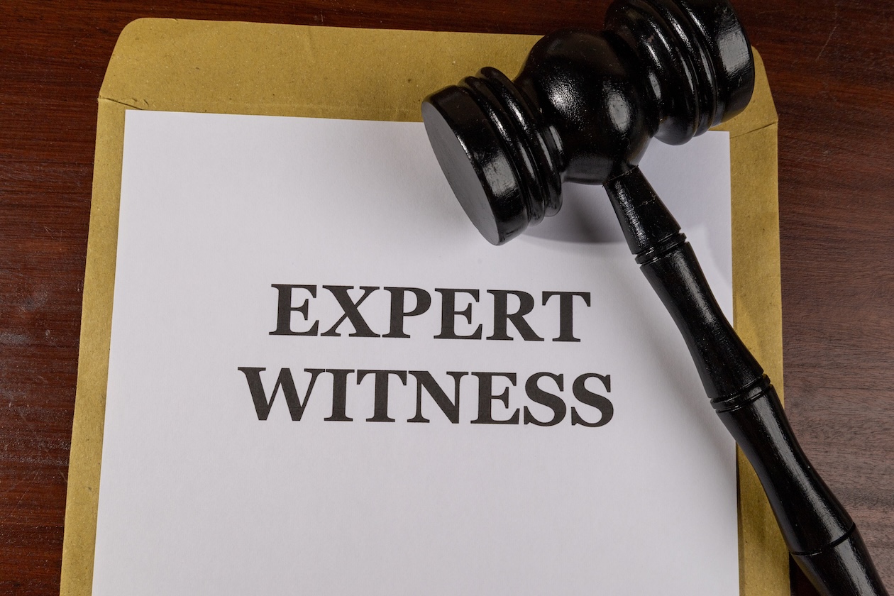 Close-up of legal documents labeled “Expert Witness” on a desk, representing expert testimony and specialized evidence in a court case.