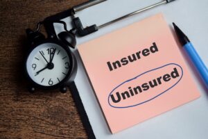 Sticky notes on a wooden table displaying the word “uninsured” inside a blue circle, representing uninsured driver accidents and auto insurance coverage issues in Nevada.