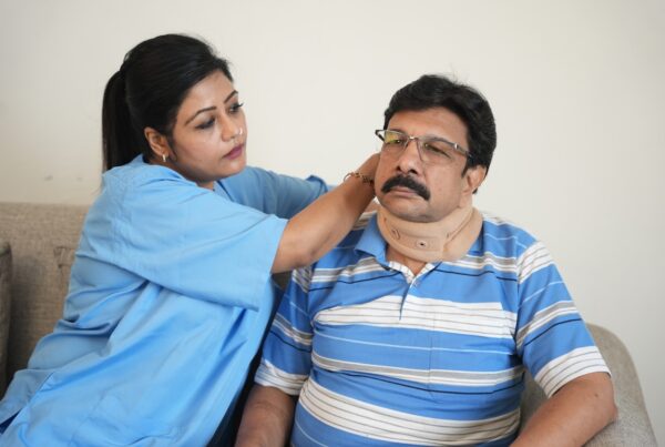 Healthcare professional adjusting a neck brace on an injured man recovering after a car accident.