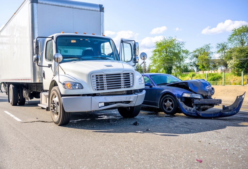 Damaged car and semi-truck with box trailer following a roadway collision.