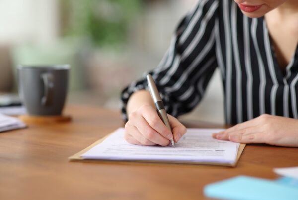 Woman signing a settlement agreement or insurance claim document at a table after a car accident.